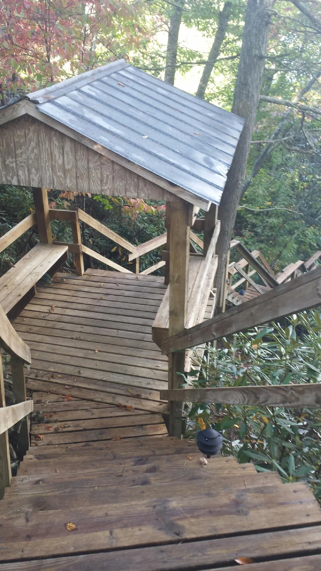 Metal roofed shelter over wooden steps on a wooded walkway — Skylight Repair & Installation work by our crew in Baldwin